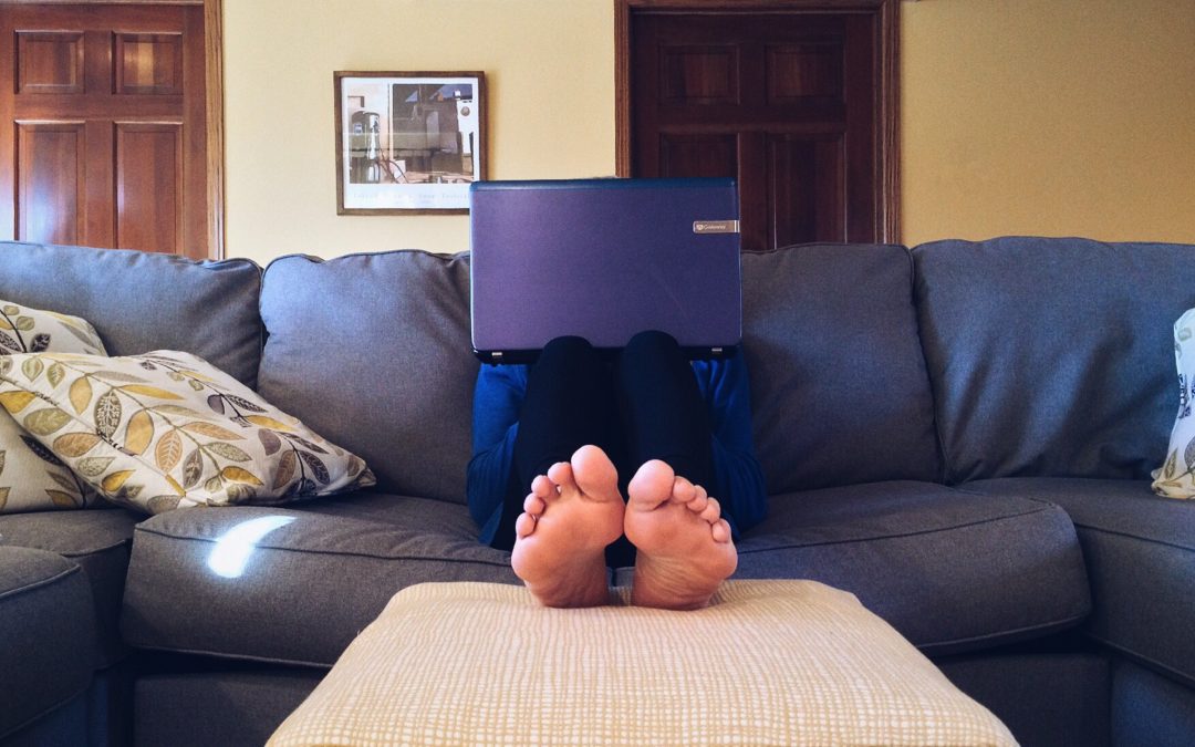 Person sitting on a sofa with their fit up and a laptop on their lap. Image used for Lisa Laporte blog about finding a work life balance